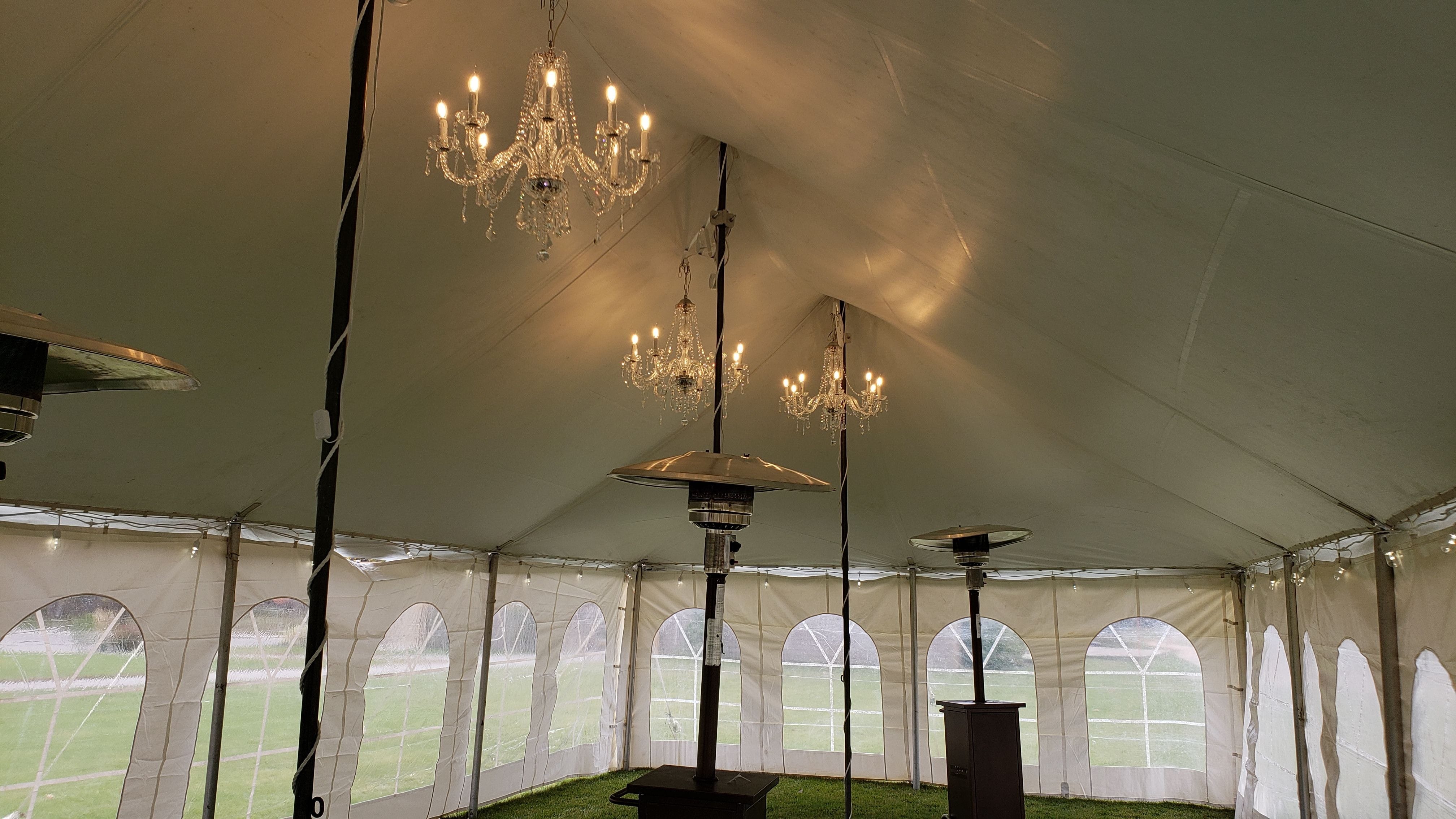 three chandeliers hang on poles inside a tent at Giants Ridge for a wedding. Lighting by Duluth Event Lighting.