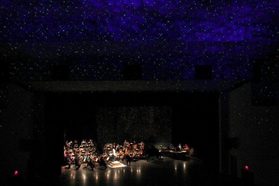 A Stage production on Old Turtle with an orchestra on stage and the entire place filled with stars.