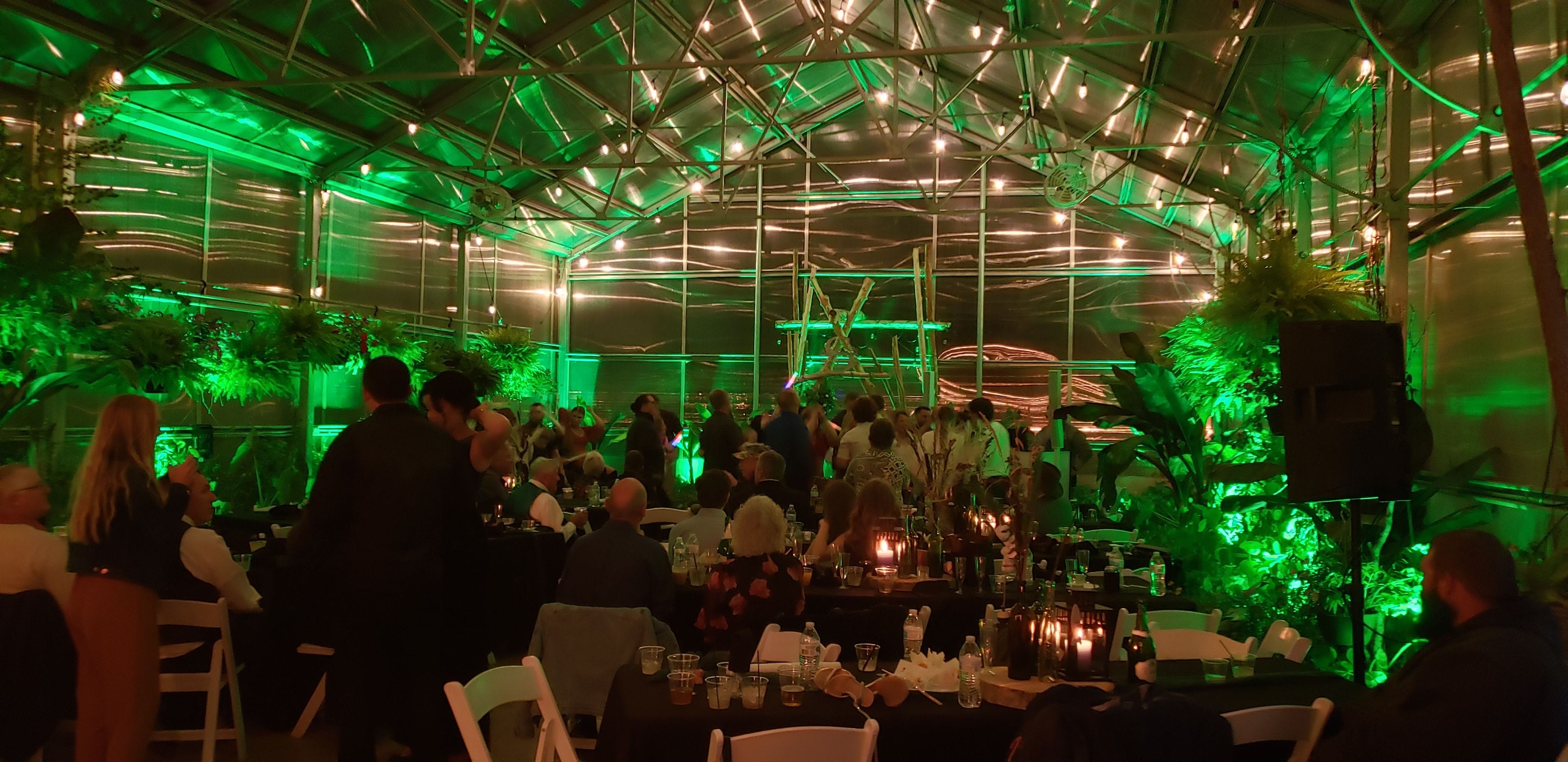 Green up lighting for a wedding reception inside the greenhouse of Sitio Events.