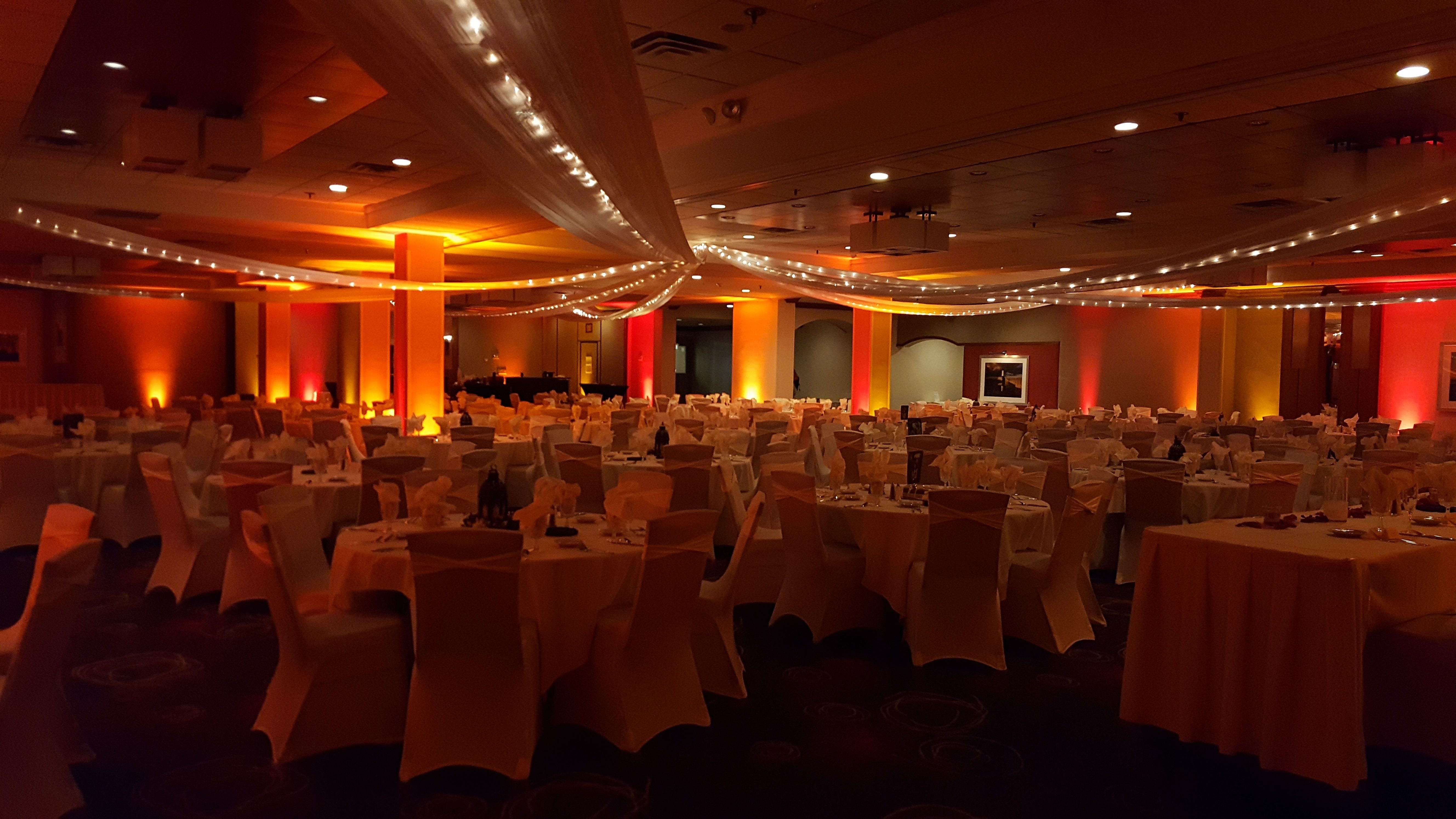 Holiday Inn wedding. Fall color theme with red, amber and orange up lighting.