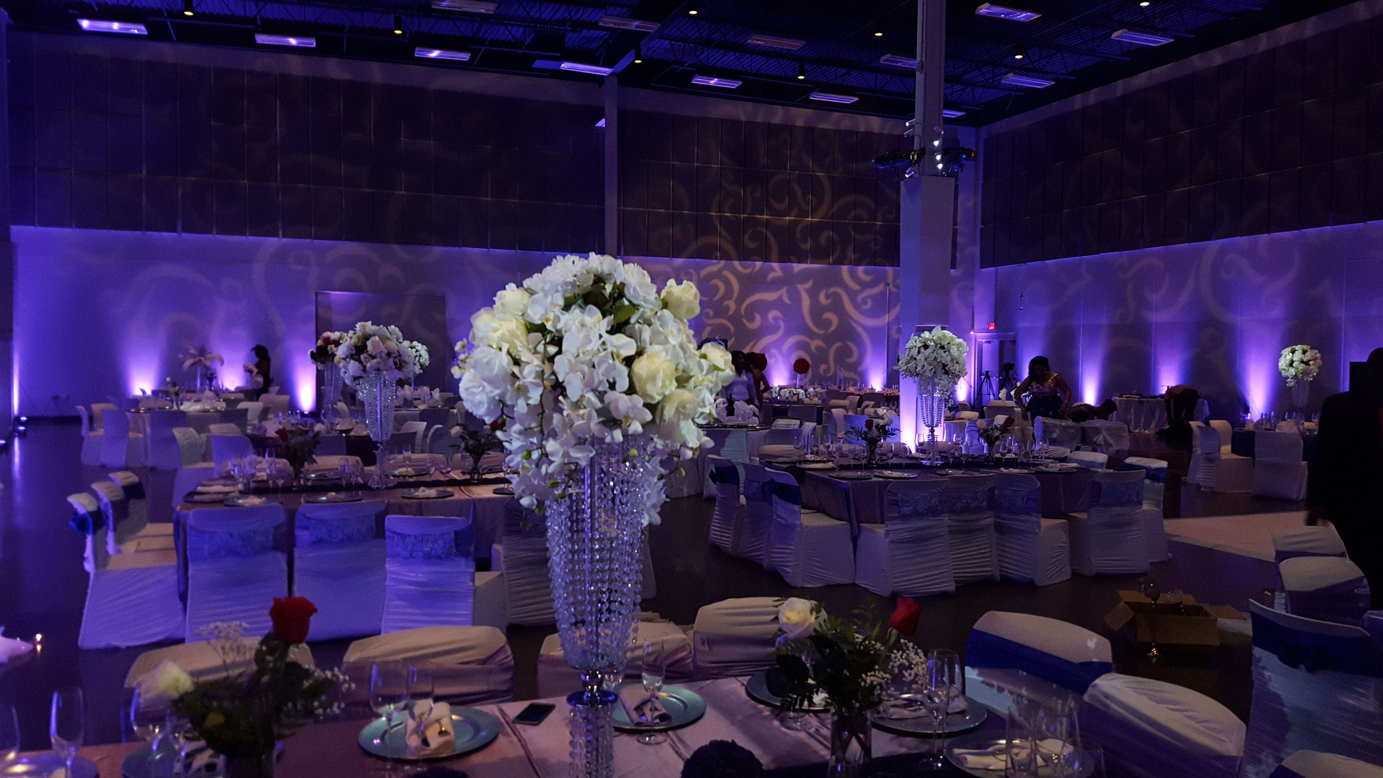 Wedding lighting at the Passion Event Center. Up lighting in lavender purple. Pin spots on flowers. Gobo pattern on the walls.