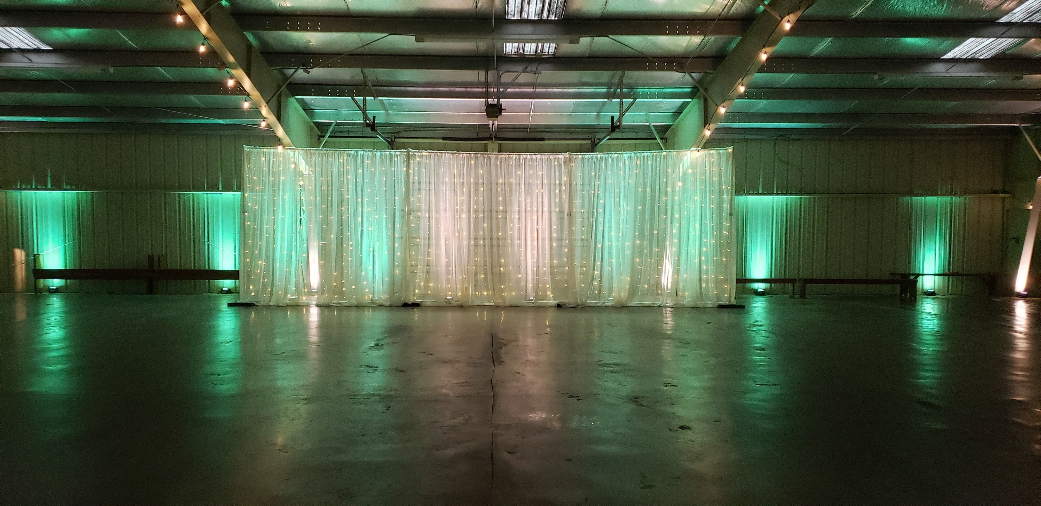 Wedding lighting at the Lakes County Fairgrounds. Up lighting in mint green and white with a head table backdrop by Duluth Event Lighting.