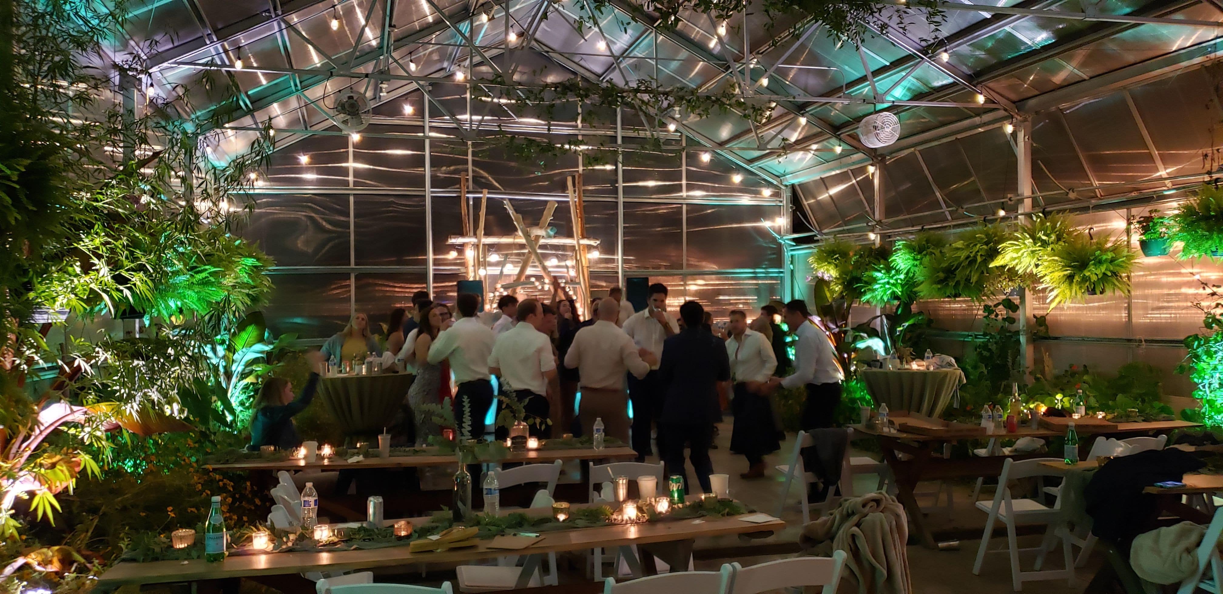 Wedding lighting with mint green and soft white up lighting inside the greenhouse of Sitio Events.