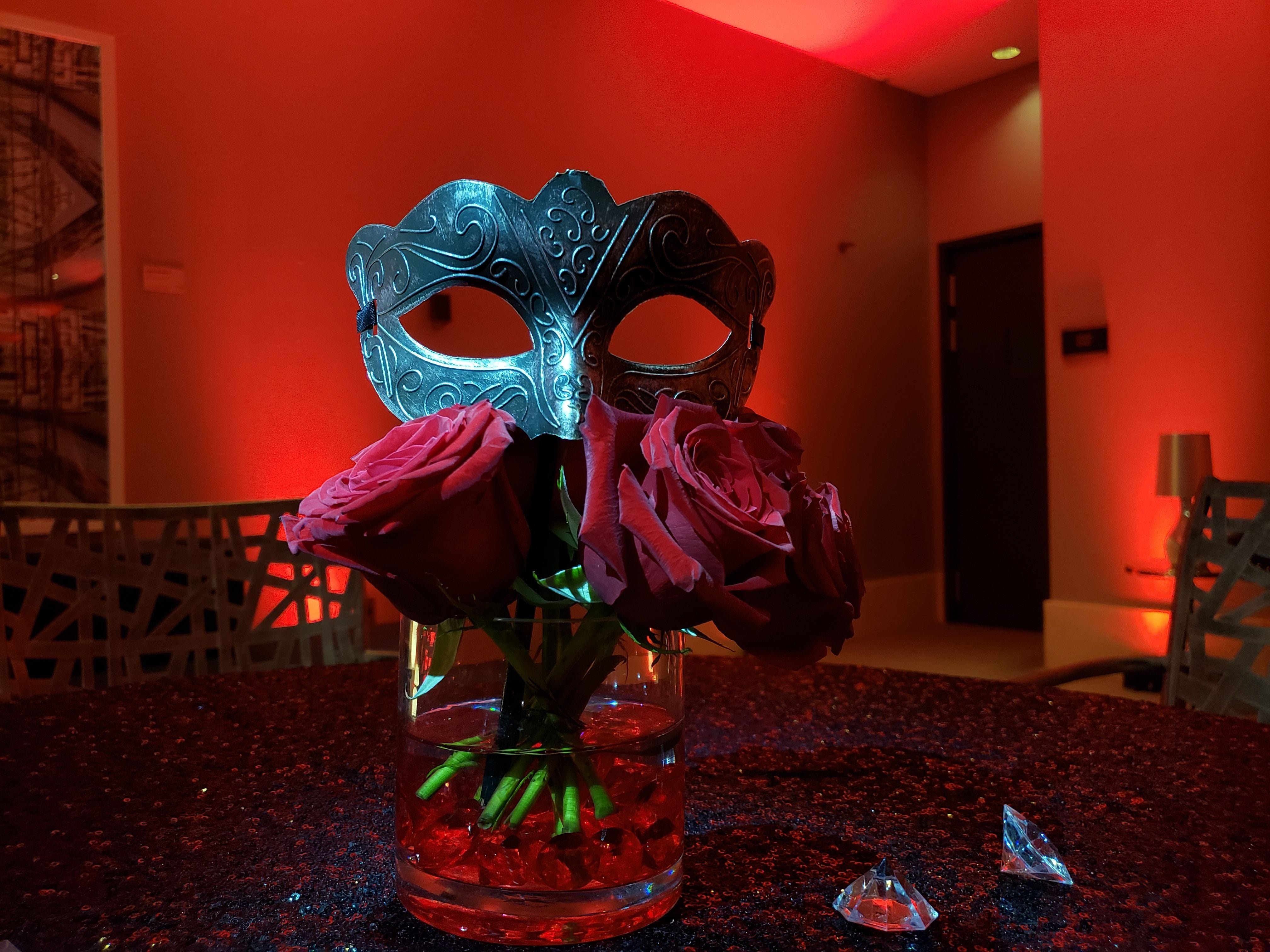 Masquerade ball. Up lighting in red. Pin spot on mask centerpeice.