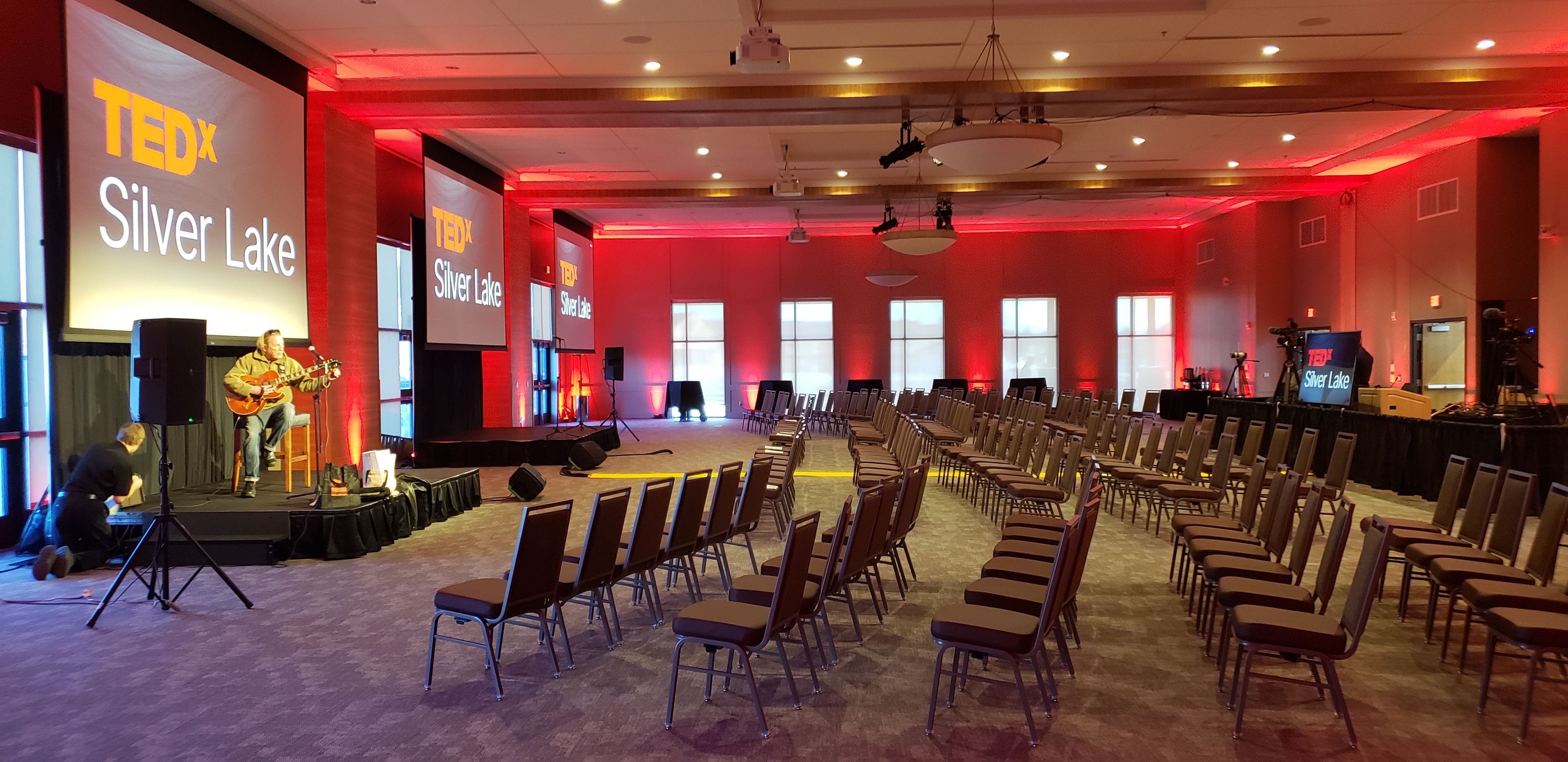 Red up lighting at the Iron Trail Motors Event Center for a Tedx talk.