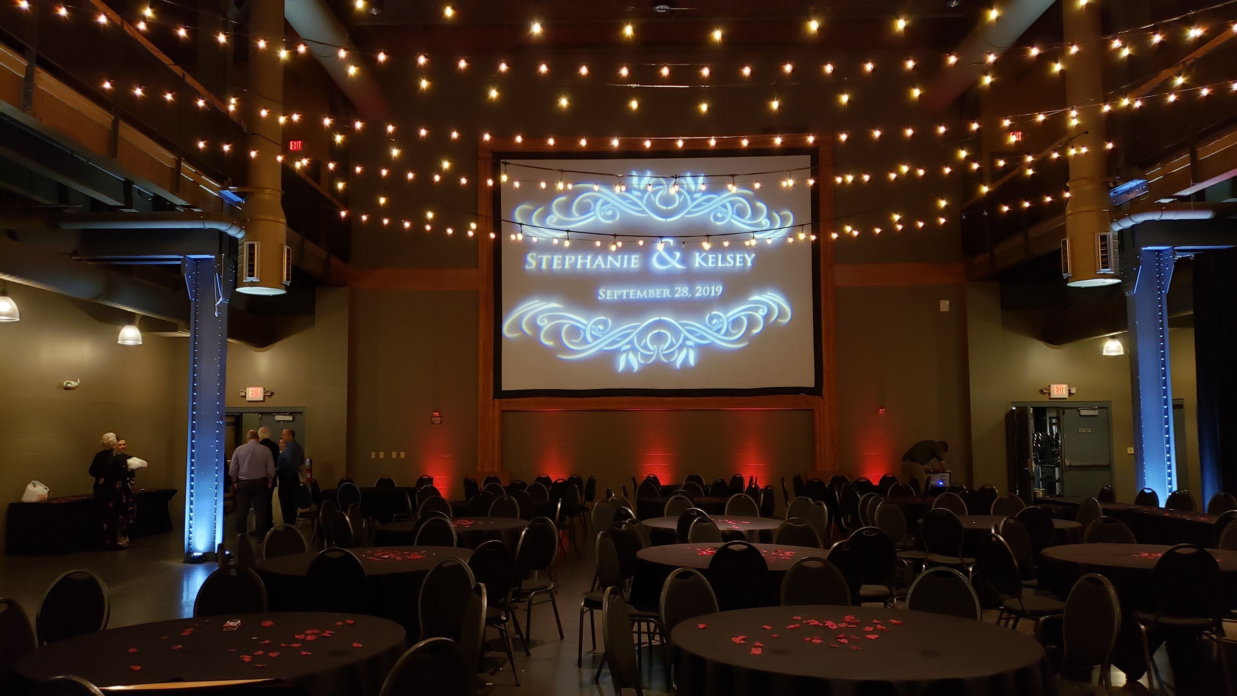 Wedding lighting in dim red at Clyde. Wedding monogram on the movie screen. Bistro