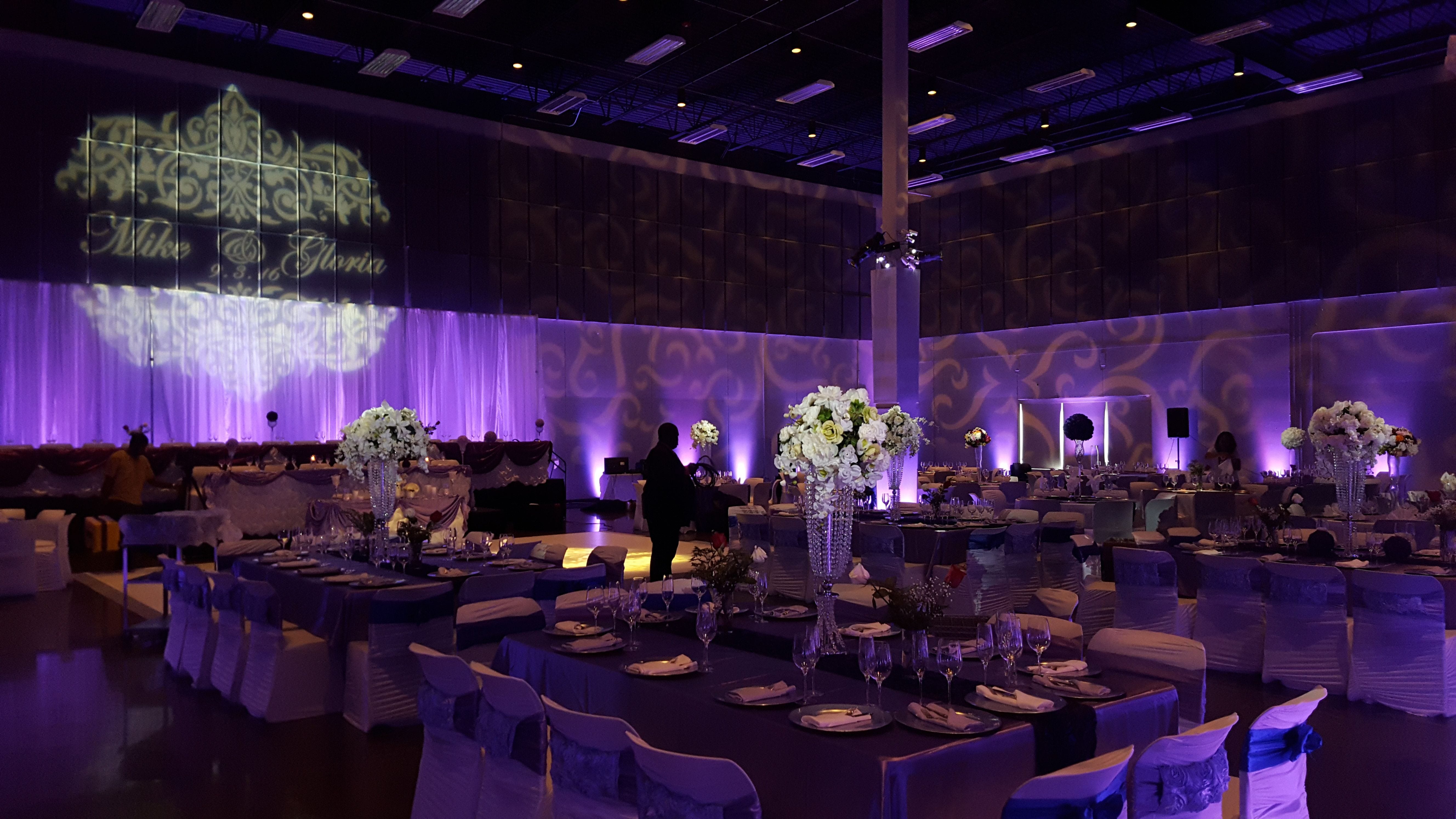 Wedding lighting at the Passion Event Center. Up lighting in lavender purple. Pin spots on flowers. Wedding monogram.