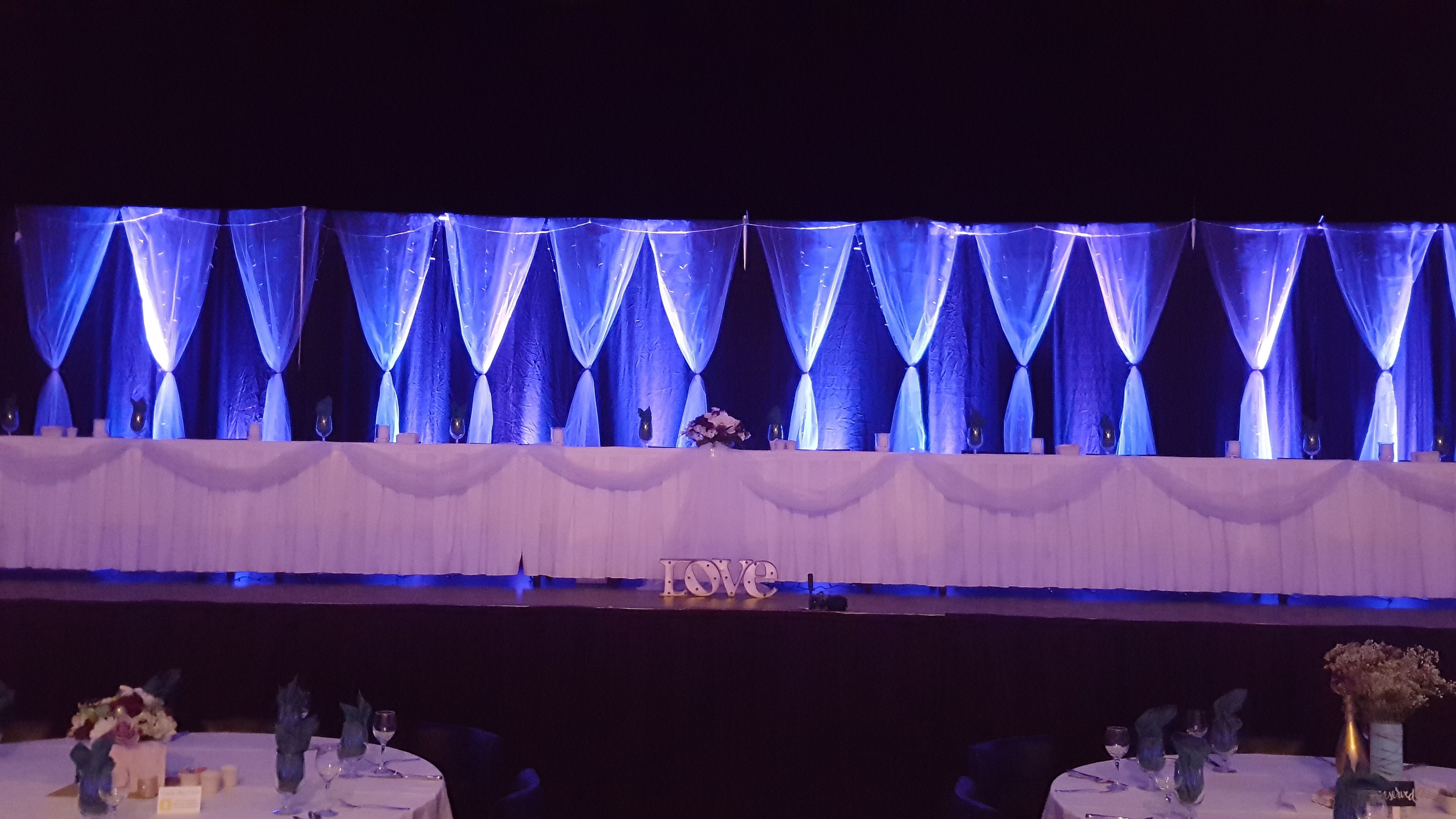A wedding head table backdrop with up lighting.