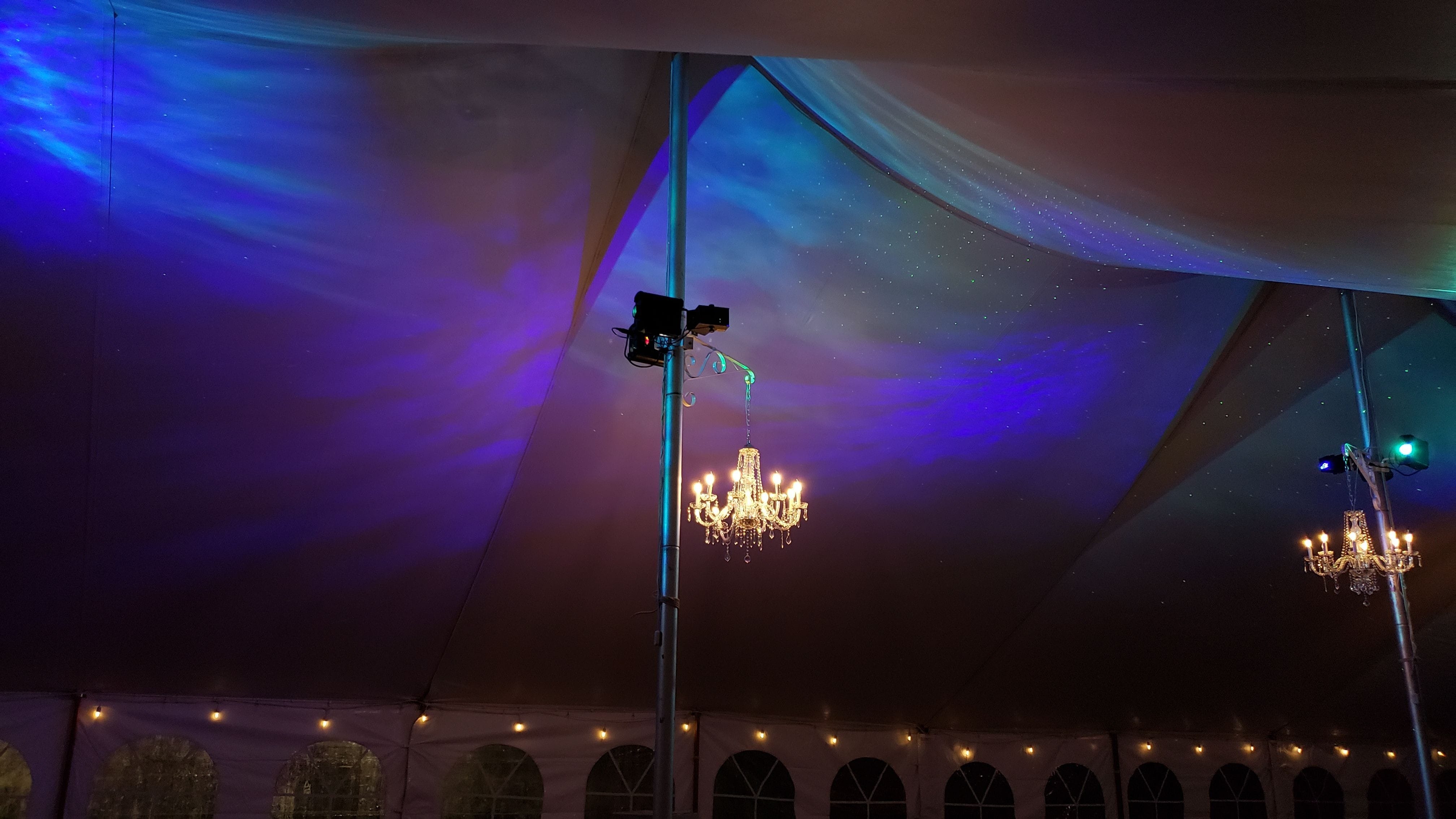 Tent wedding lighting. Four chandeliers with Stars and Northern Lights with perimeter bistro.