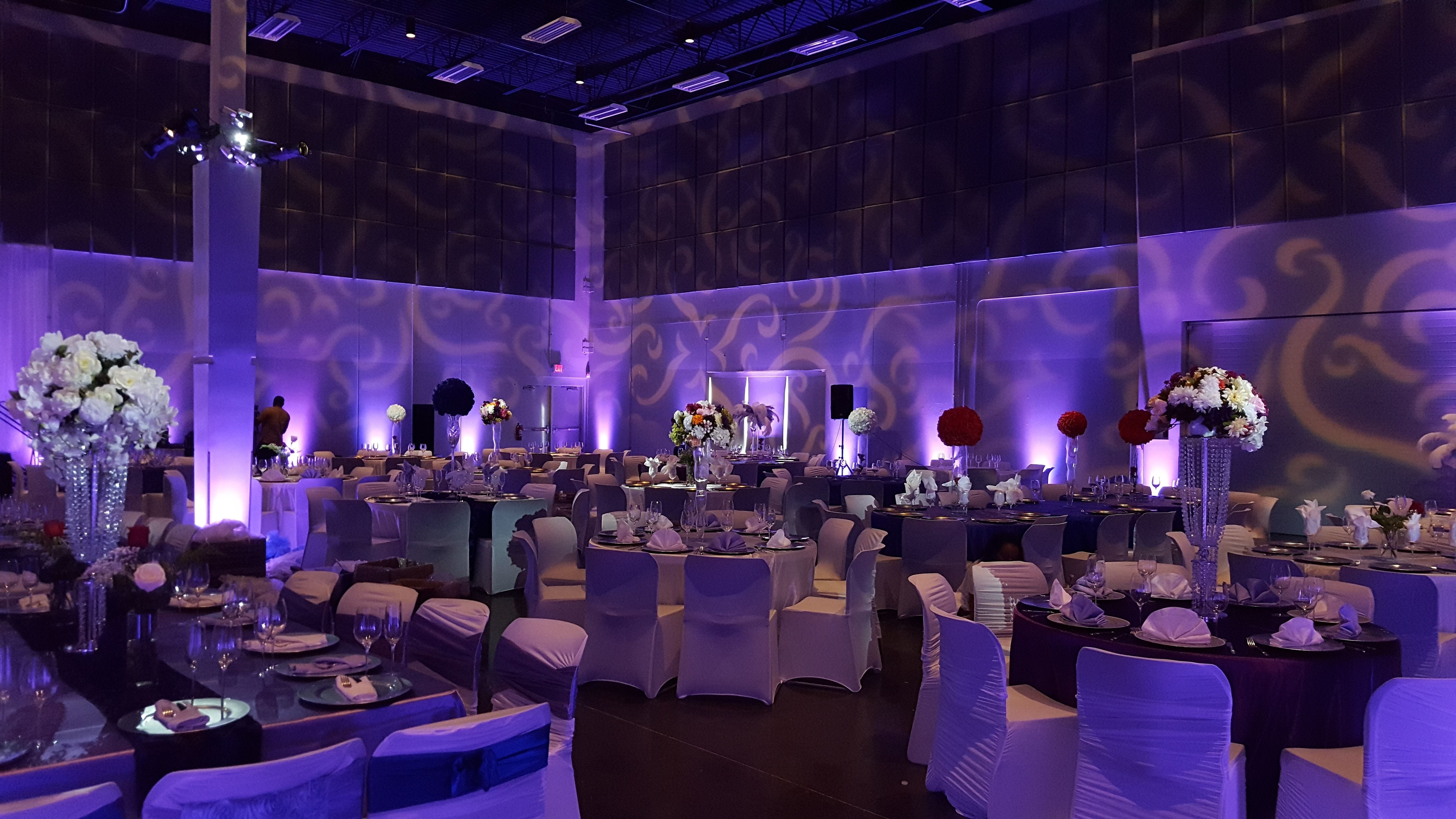 Wedding lighting at the Passion Event Center. Up lighting in lavender purple. Pin spots on flowers. Wedding monogram.