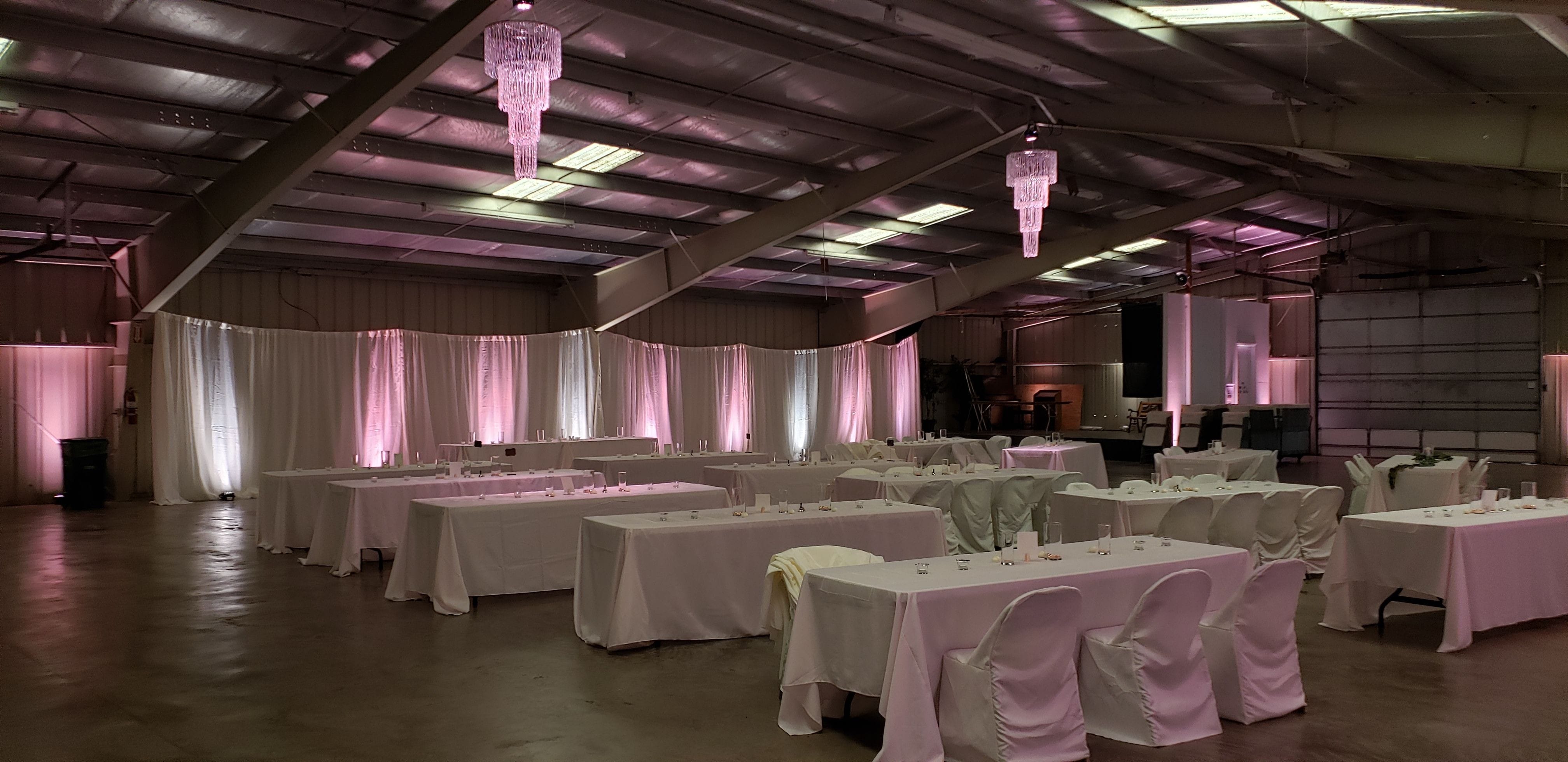 Wedding lighting at the Lake County Fairgrounds with blush pink and white up lighting and two chandeliers by Duluth Event Lighting.