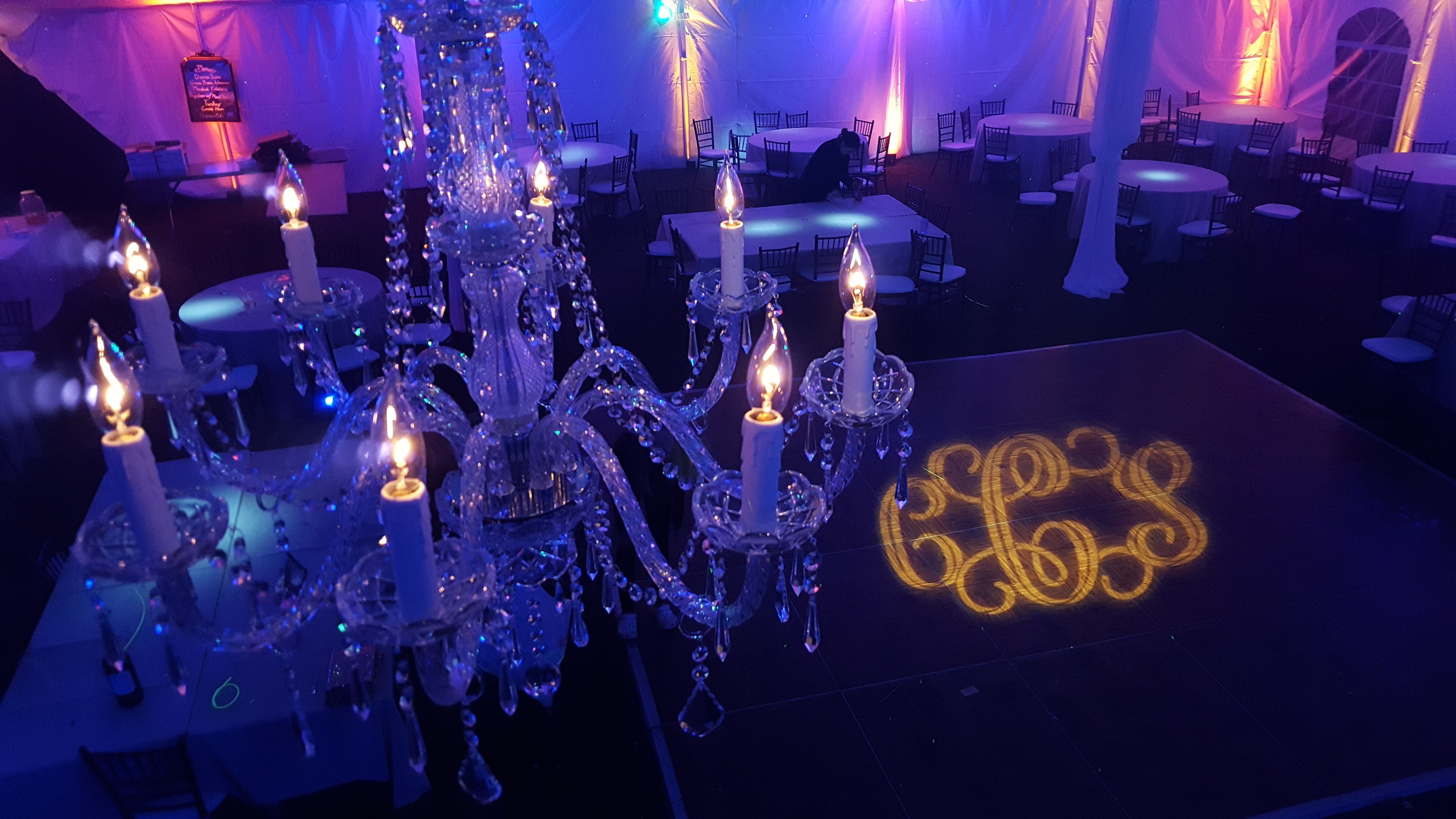 wedding lighting in a tent with up lighting and a chandelier by Duluth Event Lighting.