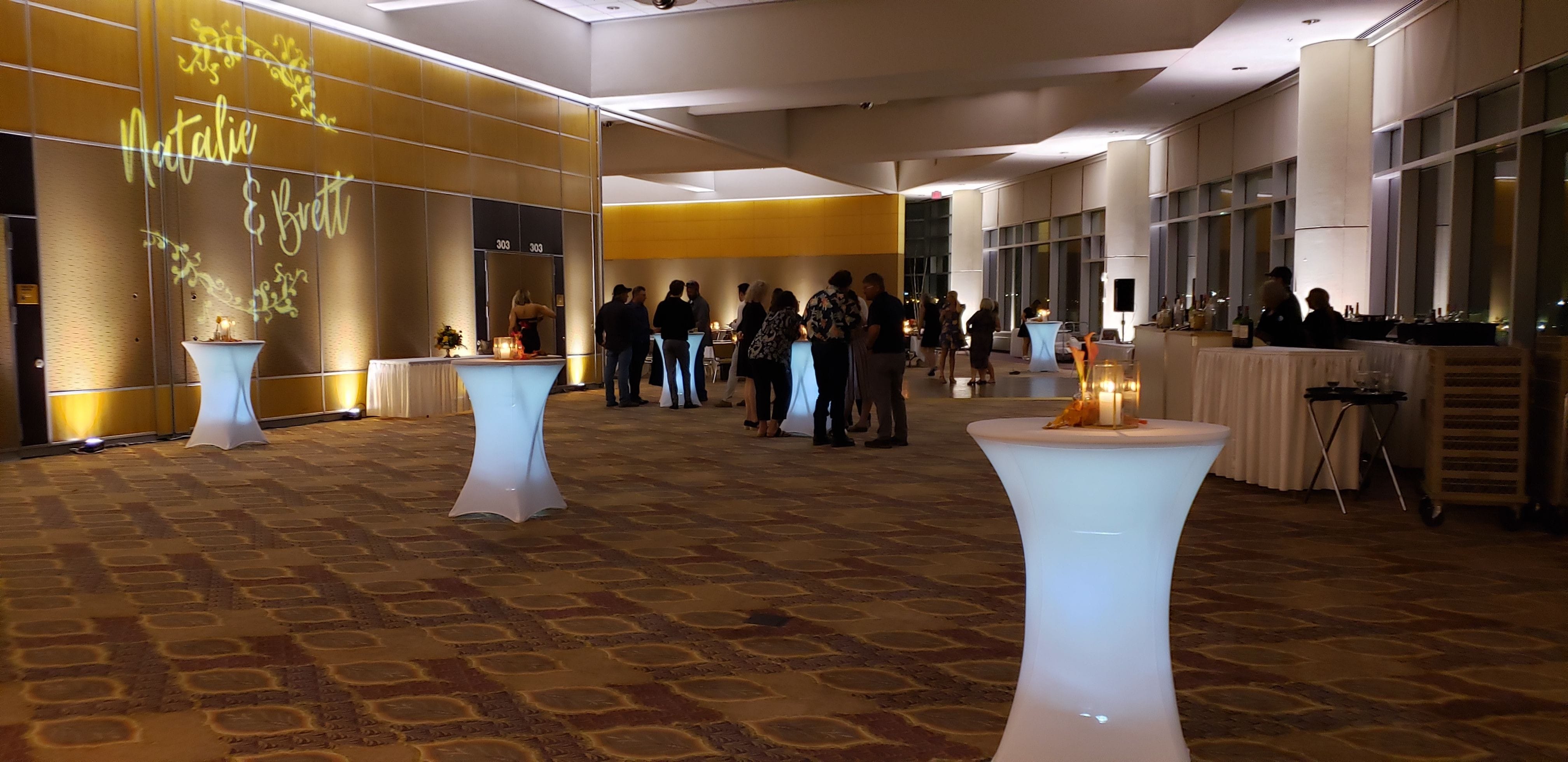 DECC Harbor Side Ballroom with white glowing cocktail tables.